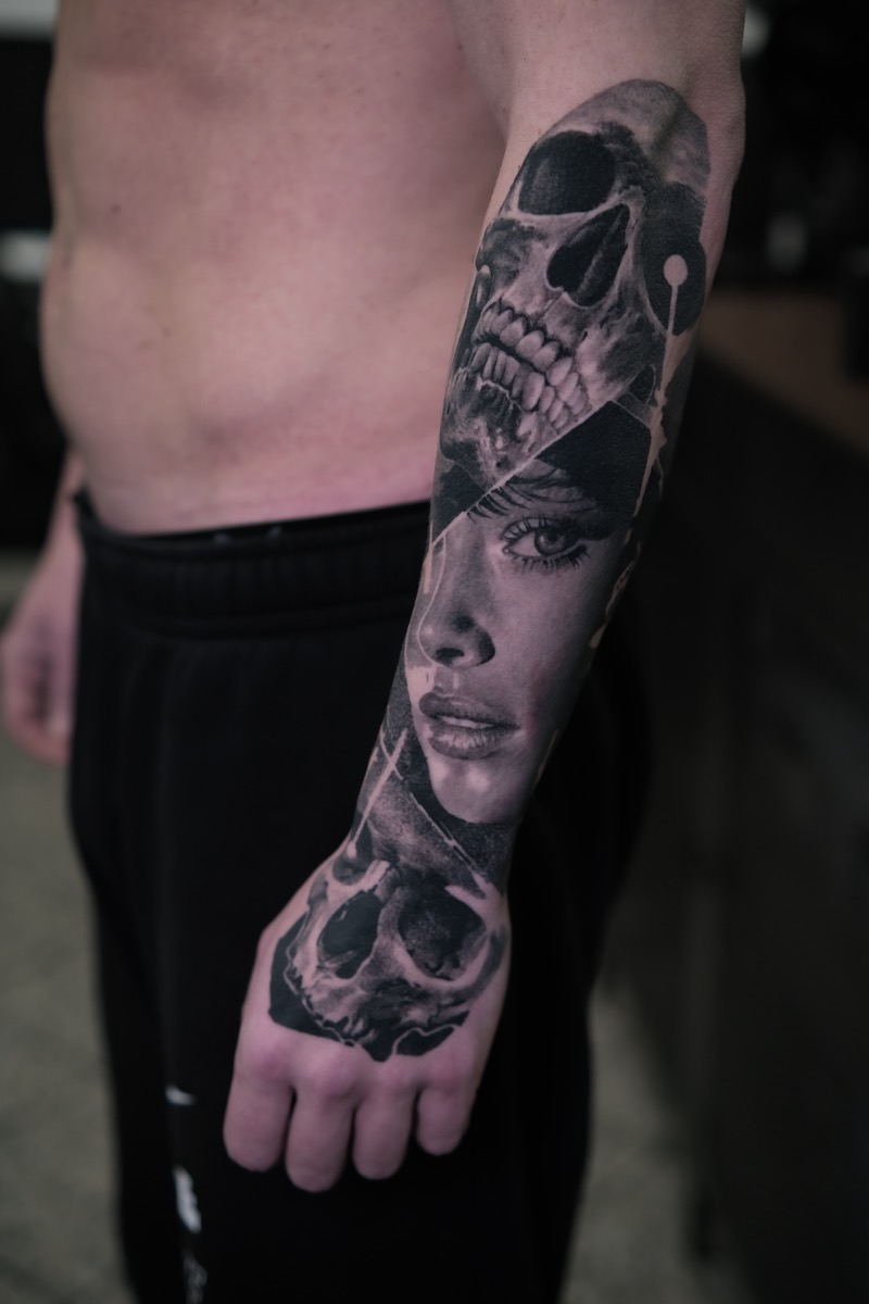 Black & Grey Tattoo an Unterarm und Hand: realistisches Frauenportrait zwischen zwei Totenköpfen mit feinen geometrischen Linien